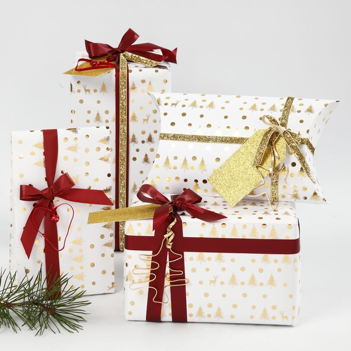Papier cadeau de Noël blanc et doré décoré avec du ruban et des formes en fil bonsaï