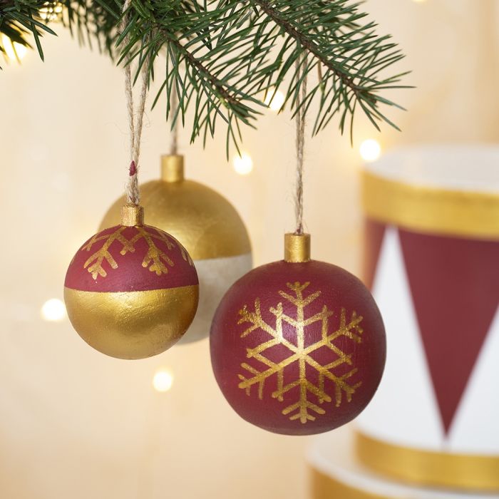Boules de Noël en bois décorées avec de la peinture de loisirs et des feutres Plus Color.