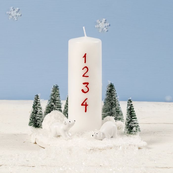 Une décoration de Noël avec une bougie, des ours polaires miniatures et des sapins de Noël.