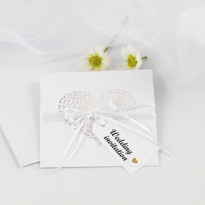 Une invitation de mariage ornée d’un ruban en satin et d’étiquettes en papier kraft, décorées de stickers en relief.