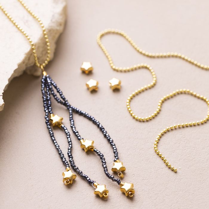 Un pompon en perles de rocaille sur un collier avec des fleurs en perles de rocaille et des perles intercalaires en forme d’étoile