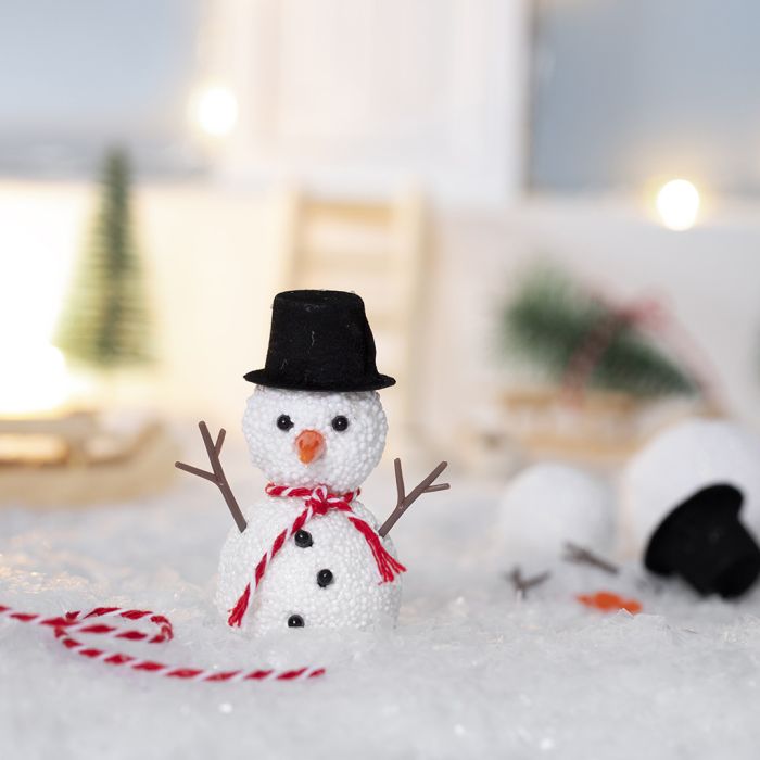 L’Elfe construit un bonhomme de neige devant sa porte d’entrée.