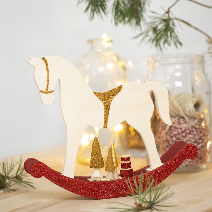 Un cheval à bascule avec de petits accessoires en bois décorés avec de la peinture de loisir créatif, des paillettes et des perles