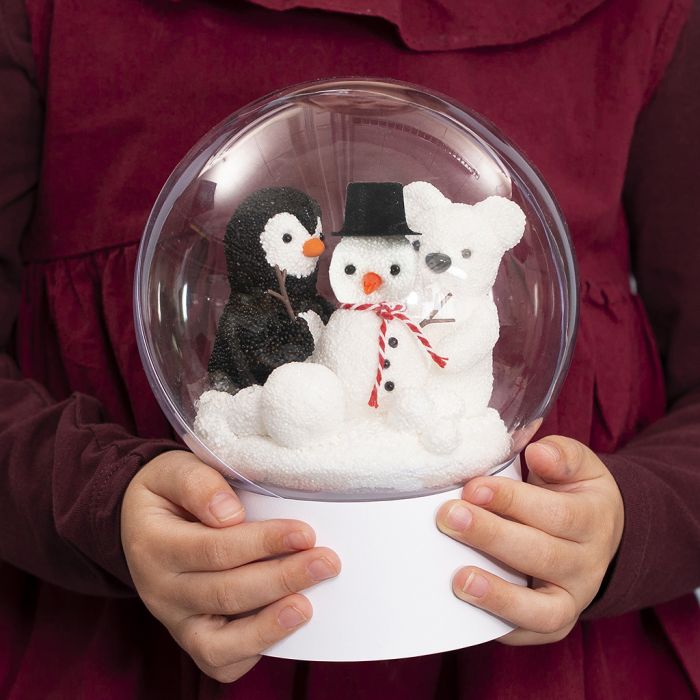 Une boule transparente sur un support avec un bonhomme de neige, un pingouin et un ours polaire à l’intérieur