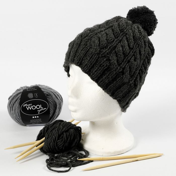 Un bonnet tricoté avec un motif torsadé et un pompon.