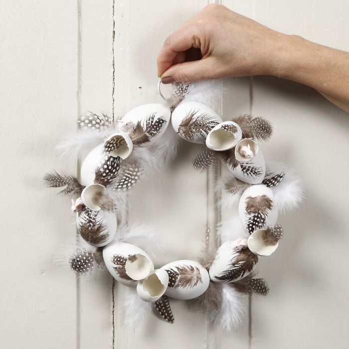 Une couronne décorée d’œufs en plastique et de plumes de pintade.