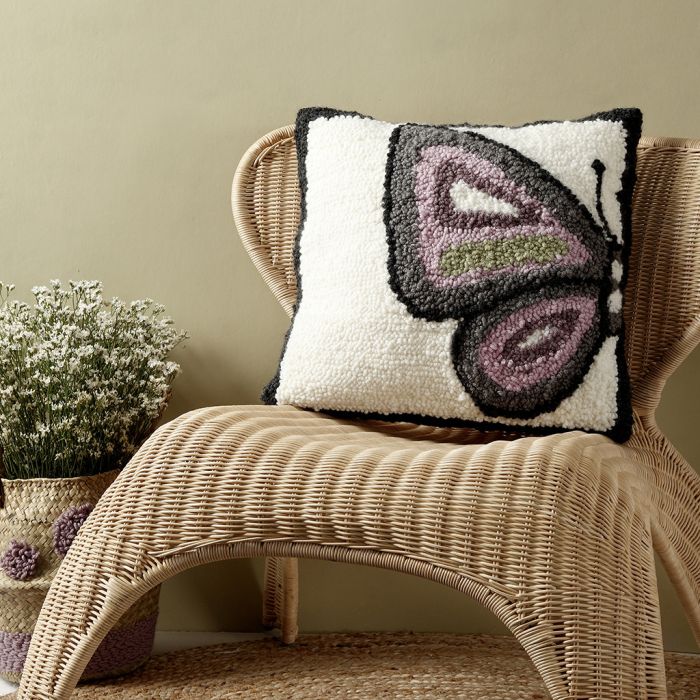 Un coussin avec un motif de papillon réalisé avec une aiguille punch