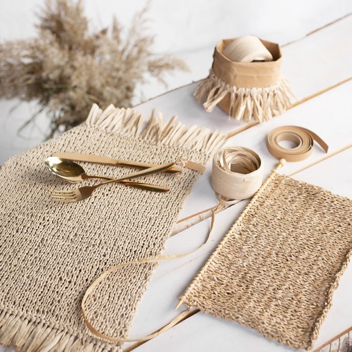 Sets de table tricotés en raphia de papier avec des pompons.