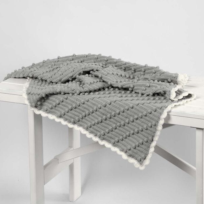 Une couverture de bébé crochetée avec des pompons en diagonales