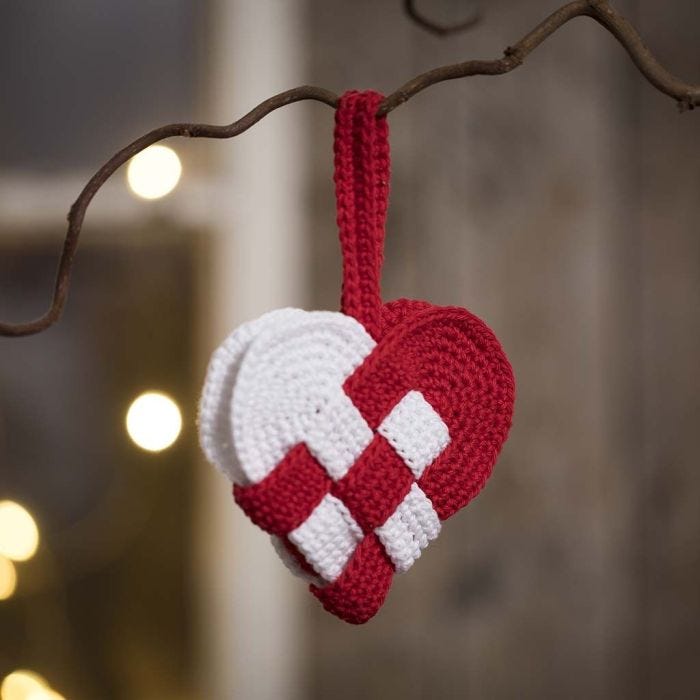 Un panier de Noël en forme de coeur, crocheté avec du fil de coton rouge et blanc