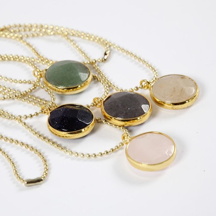 Un collier fait avec une chaîne à boules et un pendentif décoré d'une pierre