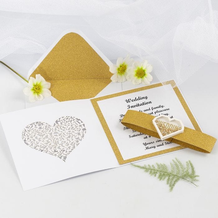 Une invitation de mariage faite avec du papier design doré à paillettes et un autocollant à secouer en forme de coeur