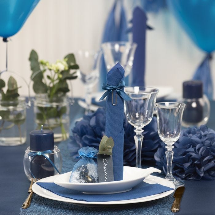 Des décorations de table bleu noir avec des fleurs en papier, des ballons, des serviettes pliées en forme de tours et des marque-places