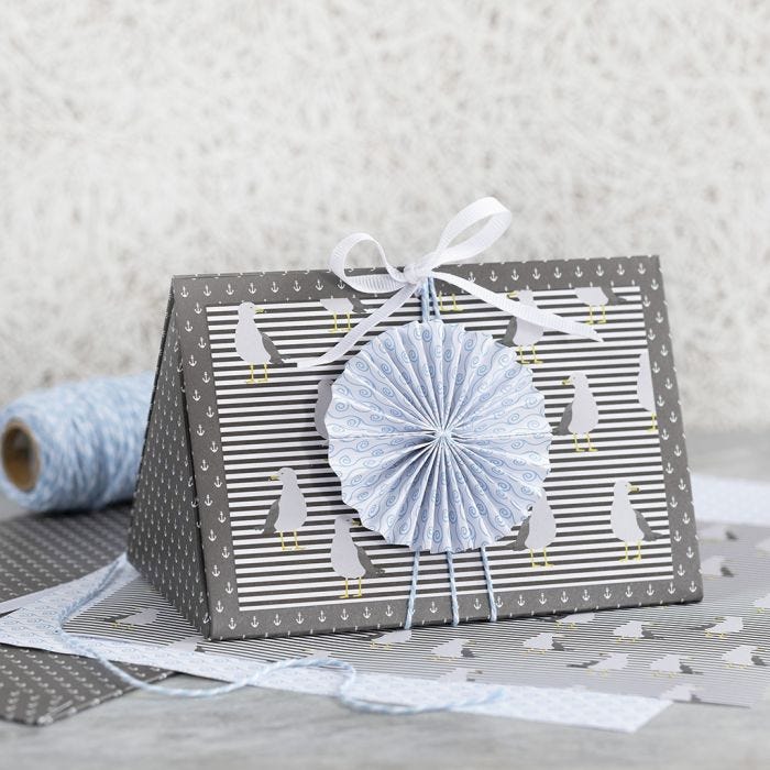 Une boîte cadeau bleu noir, décorée d'une rosette bleue et de papier design