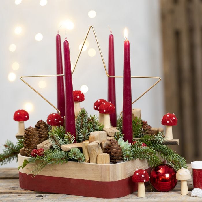 Une couronne de l'Avent décorée d'une étoile métallique, de crapauds, d'épinettes, de pommes de pin et de bouts de bois