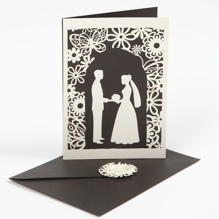 A wedding invitation with a punched-out wedding design and laced card