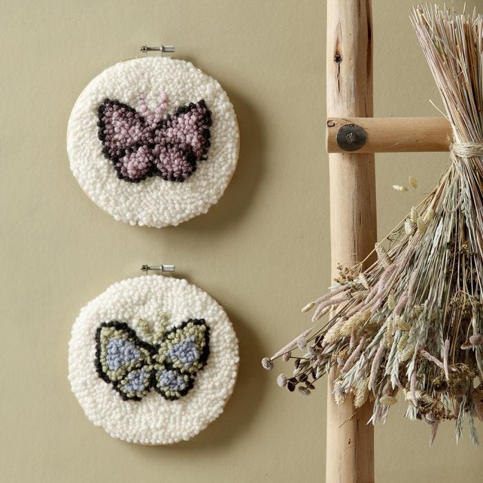 Des papillons brodés au poinçon à broderie dans un cadre à broder