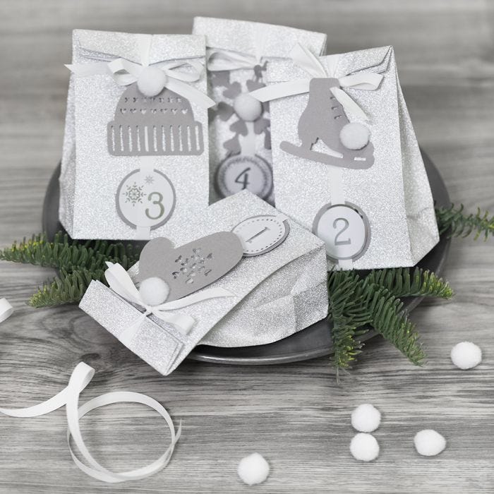 Réalisez un calendrier de l'Avent en emballant les cadeaux avec du papier décoratif et en les ornant de pompons et d'autres décorations en papier pour une présentation festive et créative