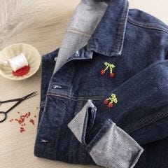 Des cerises brodées avec des perles sur une veste en jean
