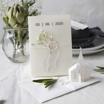Une invitation dans des tons blanc cassé avec une église découpée à l’emporte-pièce et du papier calque.