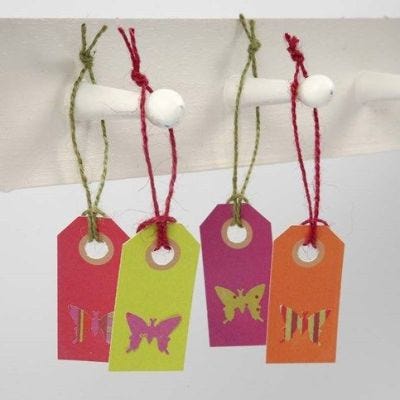 Un papillon perforé à partir de papier design et collé sur une étiquette
