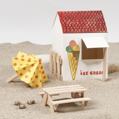 Un parasol et une table de pique-nique avec deux bancs faits avec des bâtons de glace
