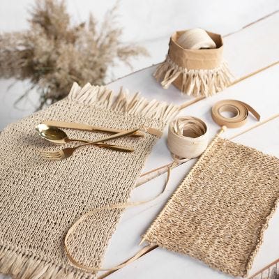 Sets de table tricotés en raphia de papier avec des pompons.