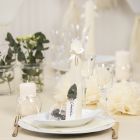 Des décorations de table blanc cassé avec des fleurs en papier, des ballons, des serviettes pliées en forme de tours et des marque-places