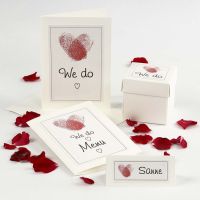 Une invitation de mariage et des décorations de table avec des coeurs d'empreintes digitales