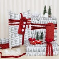 Du papier cadeau de Noël décoré avec des pompons et des figurines miniatures