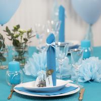 Des décorations de table bleu clair avec des fleurs en papier, des ballons, des serviettes pliées en forme de tours et des marque-places