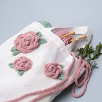 Un sac à provisions décoré de roses faites à partir d'un tube tricotés
