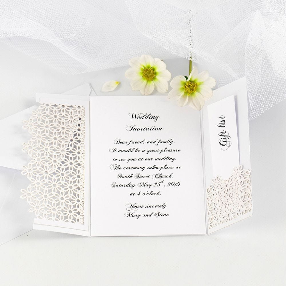 Une invitation de mariage pliée en deux decorée avec du papier cartonné à motif de dentelle