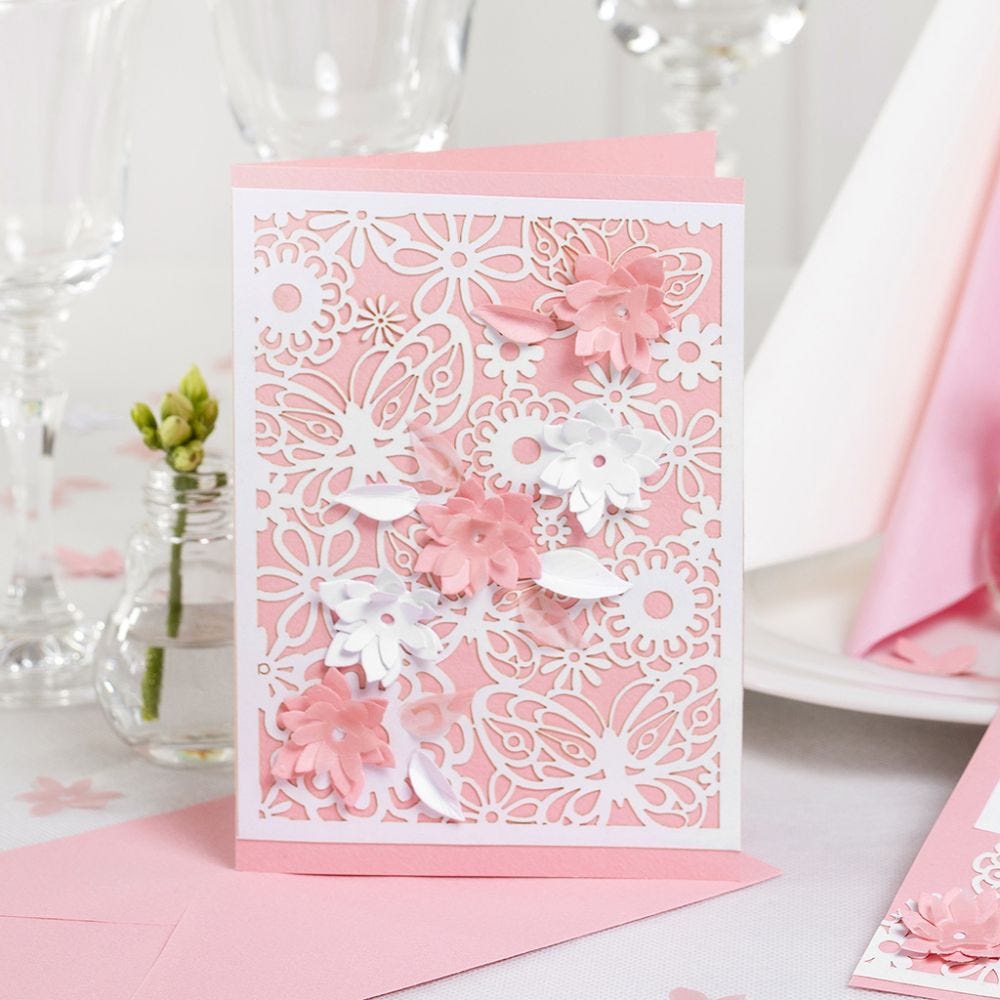 Une invitation décorée de papier cartonné à motif dentelle et de fleurs poinçonnées avec un effet 3D