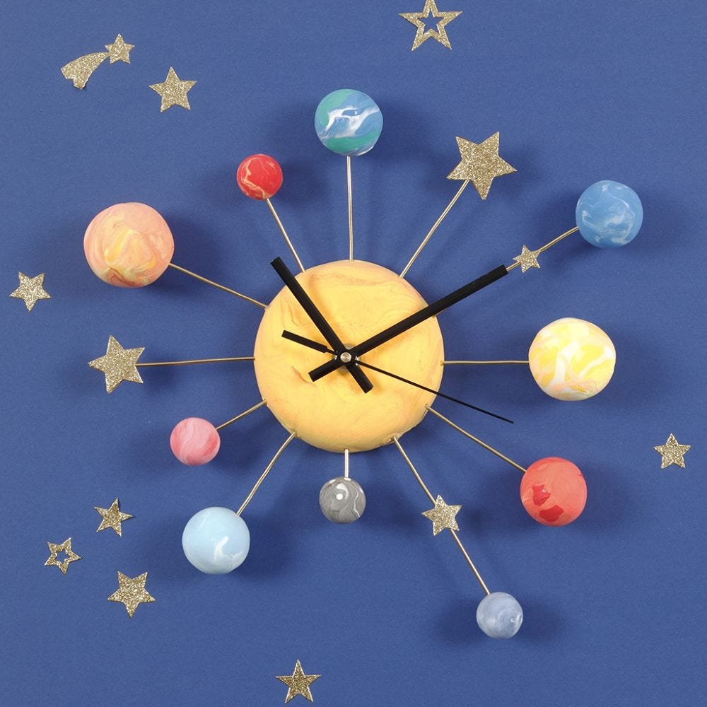 Une horloge murale décorée avec des planètes en pâte Silk Clay, des étoiles autocollantes et du fil d'aluminium